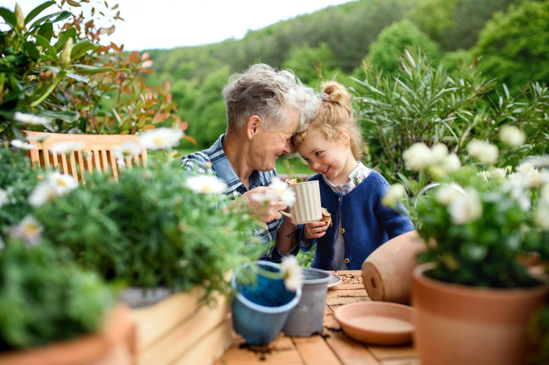 Une grand-mère et sa petite-fille attablées dans un jardin verdoyant