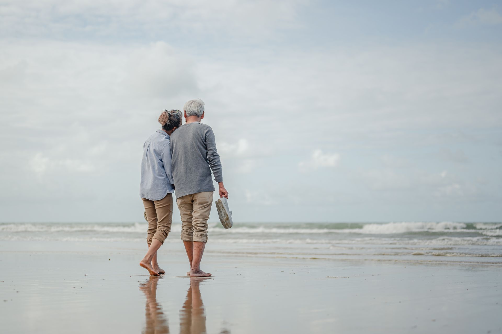 Un couple retraité marche pieds nus sur la plage