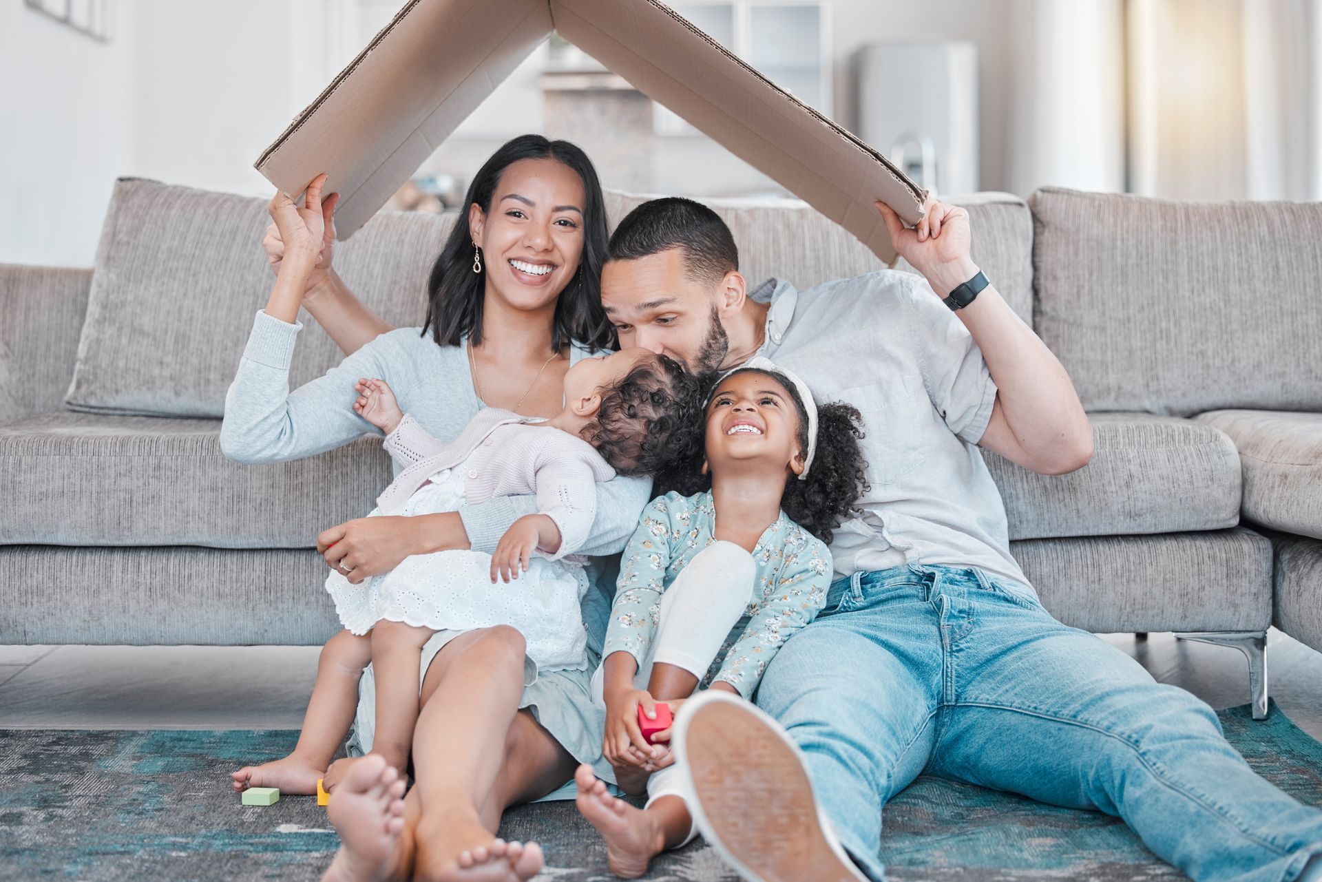 Une famille mime l'assurance habitation en se protégant sous un carton plié en forme de toit
