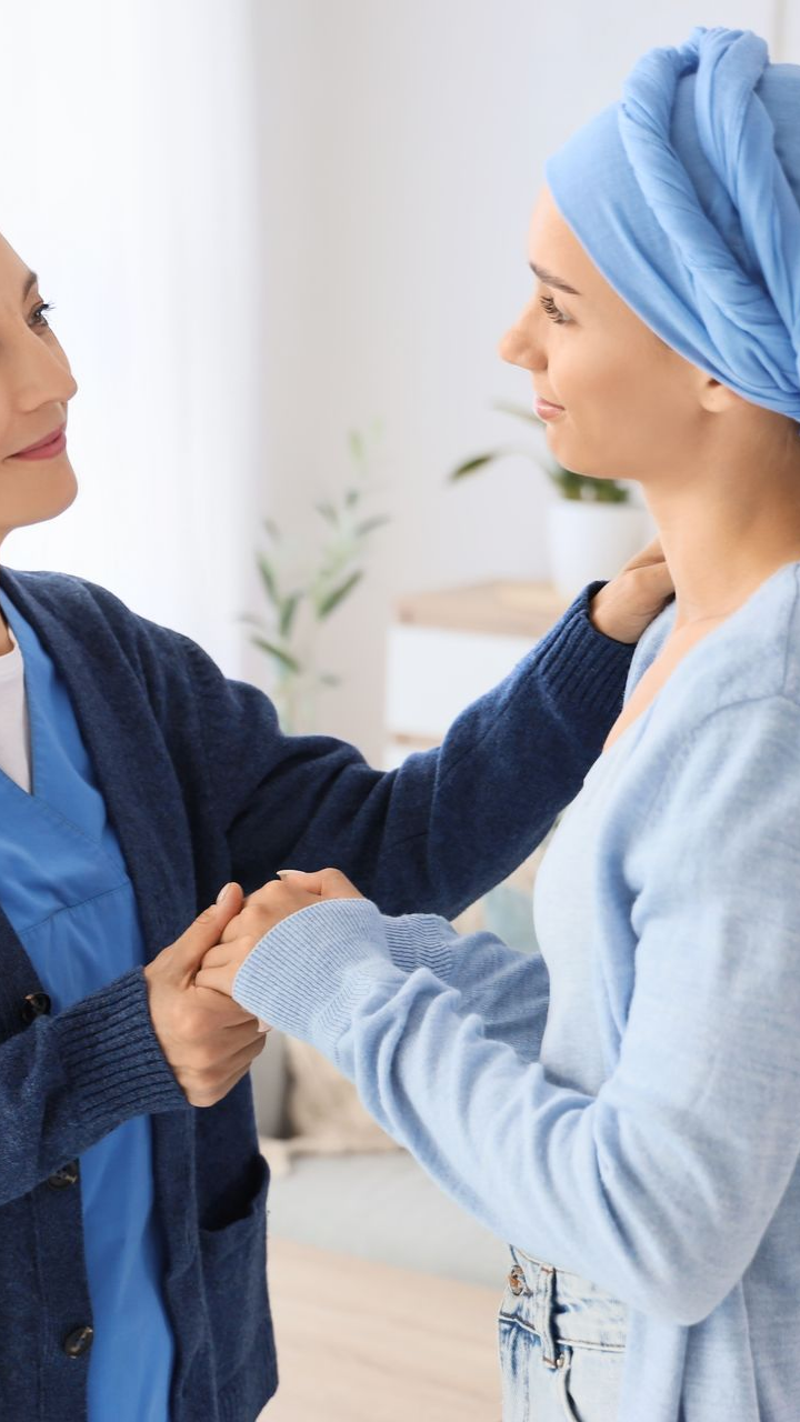 Un professionnel de la santé réconforte une femme portant un foulard bleu, probablement après une chimiothérapie.