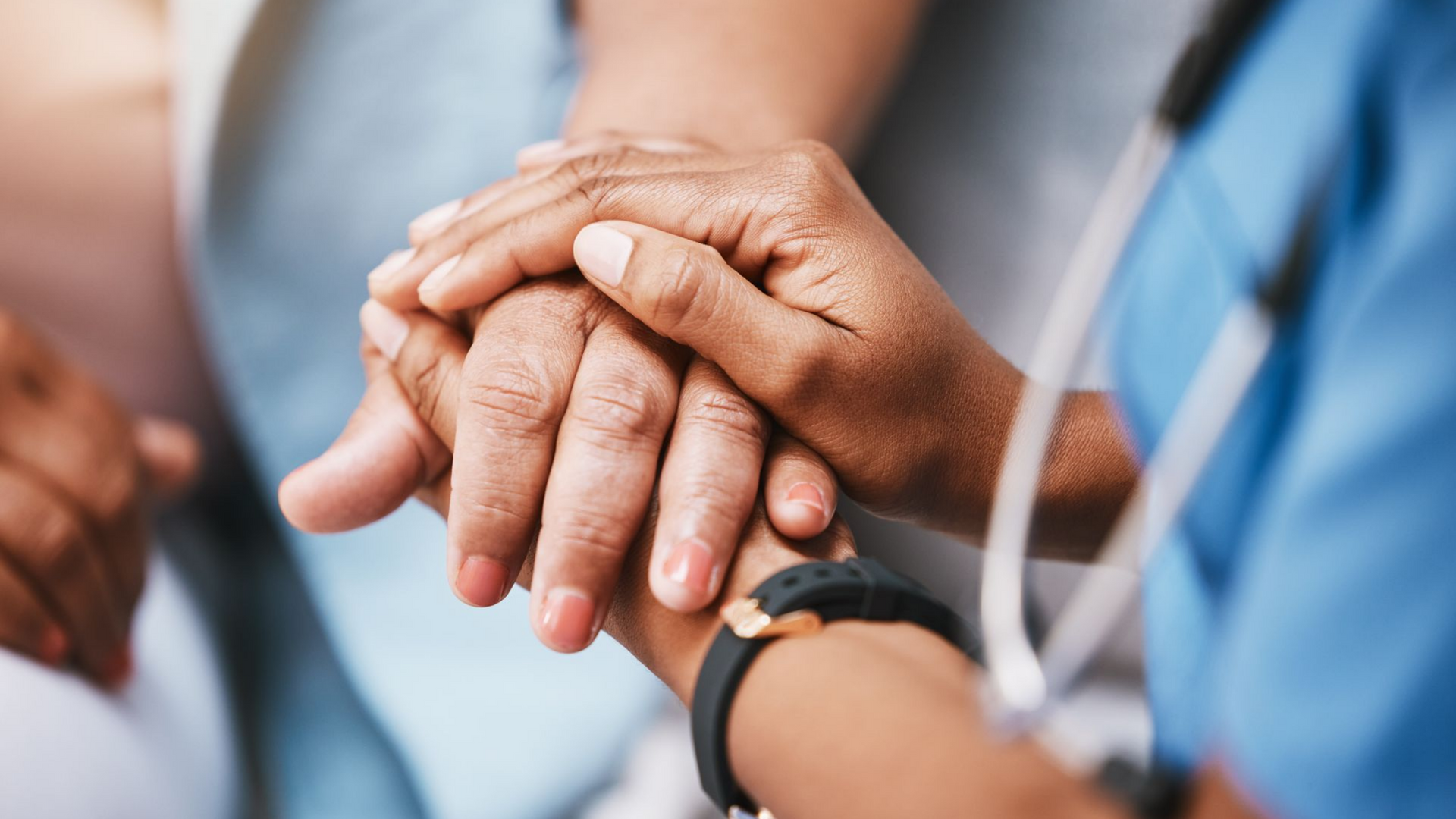 La main d'un professionnel de la santé tenant doucement la main d'un patient, lui offrant du réconfort.