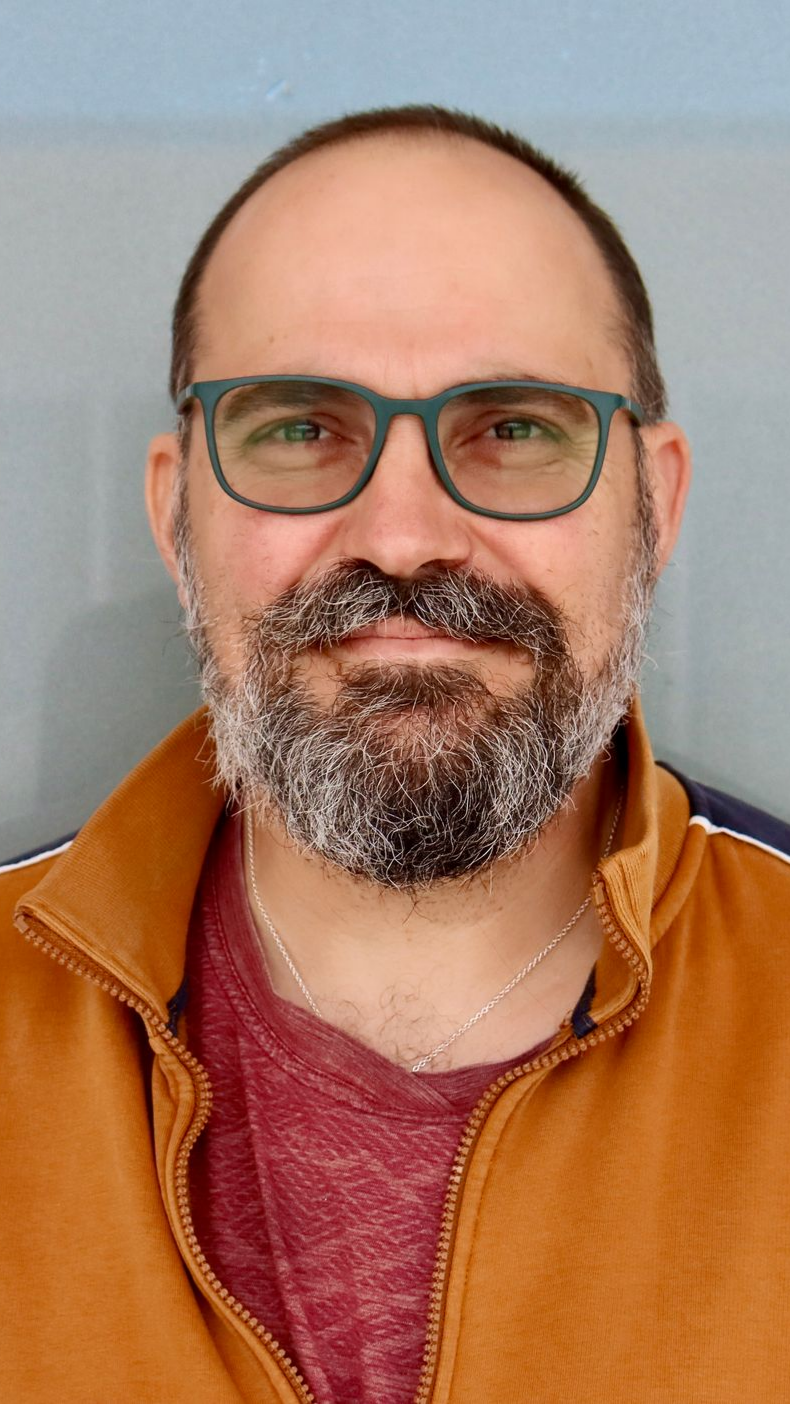 Un médecin souriant en tenue bleue consulte un patient dans une pièce bien éclairée.