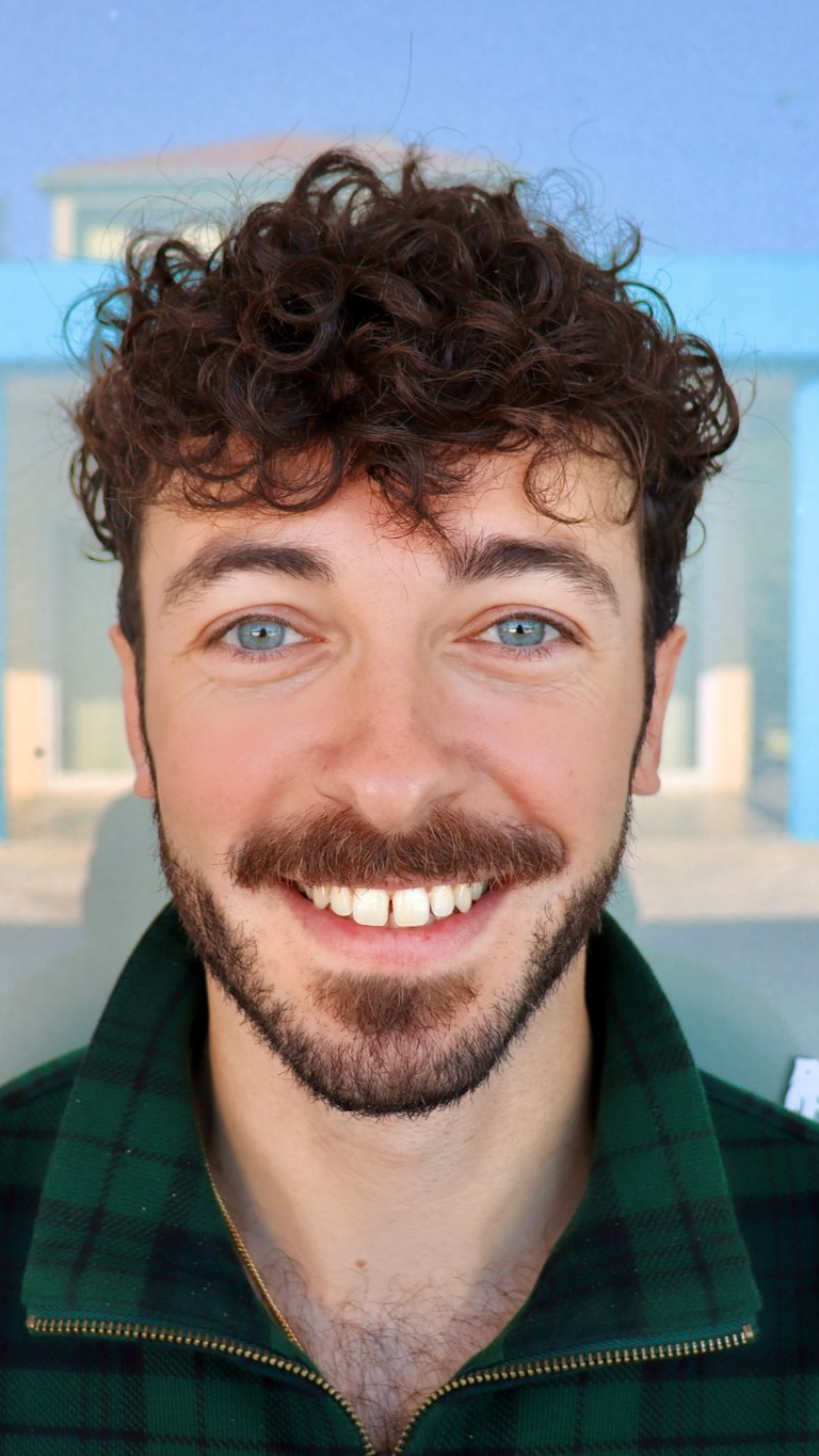Un médecin souriant en tenue bleue consulte un patient dans une pièce bien éclairée.