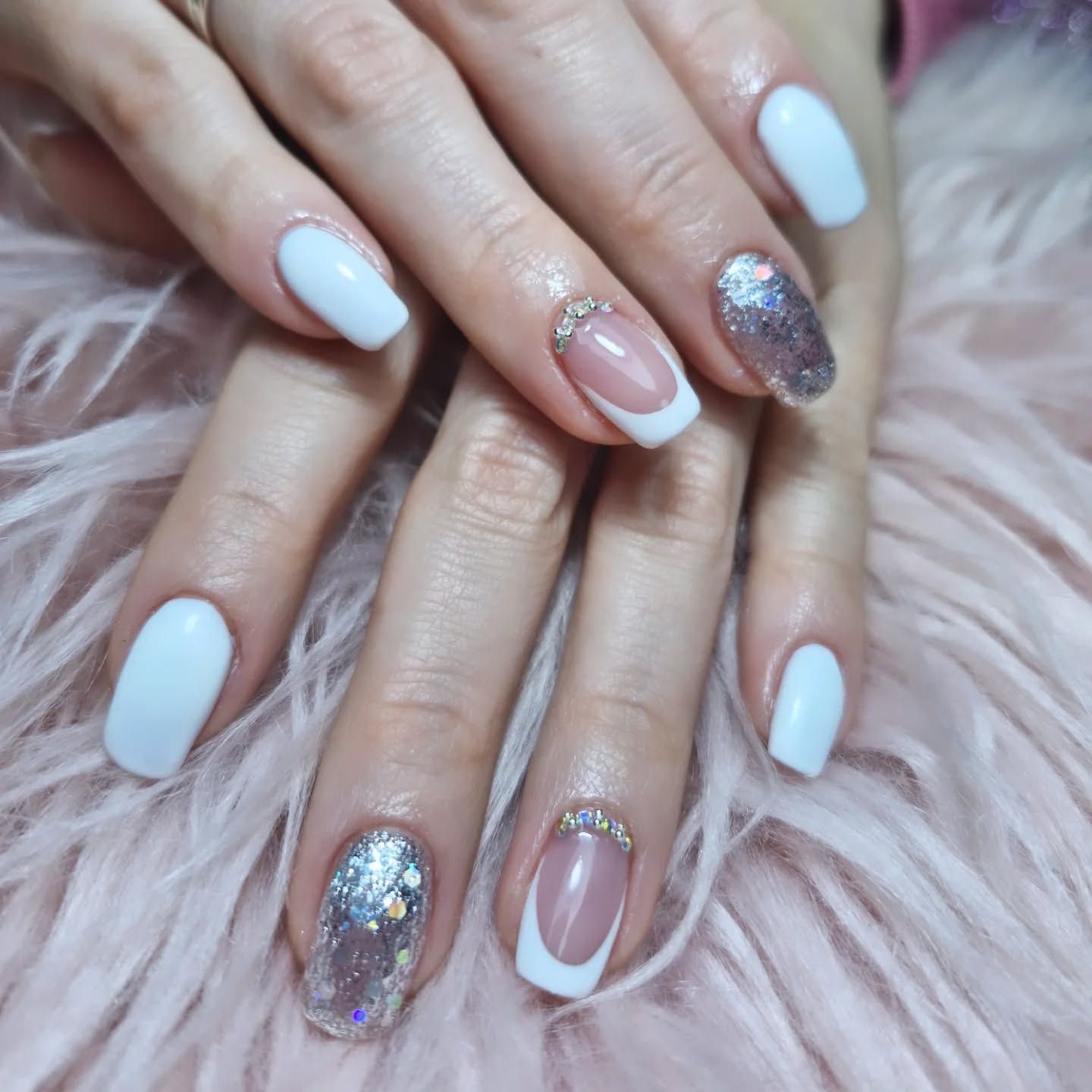 Manos con manicura azul pastel y rosa con purpurina sobre un fondo rosa esponjoso