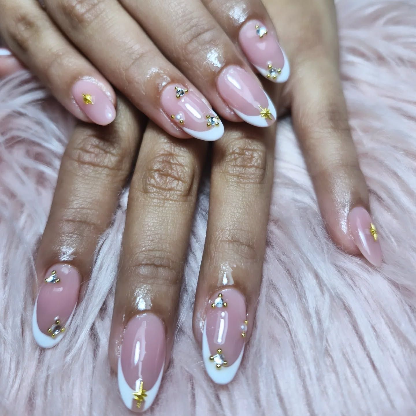 Manos con manicura rosa y detalles dorados sobre un fondo de suave pelaje rosa