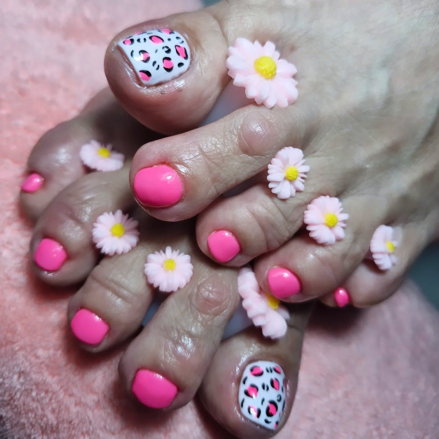 Manos con uñas rosas y dibujos de margaritas abrazándose con cariño.