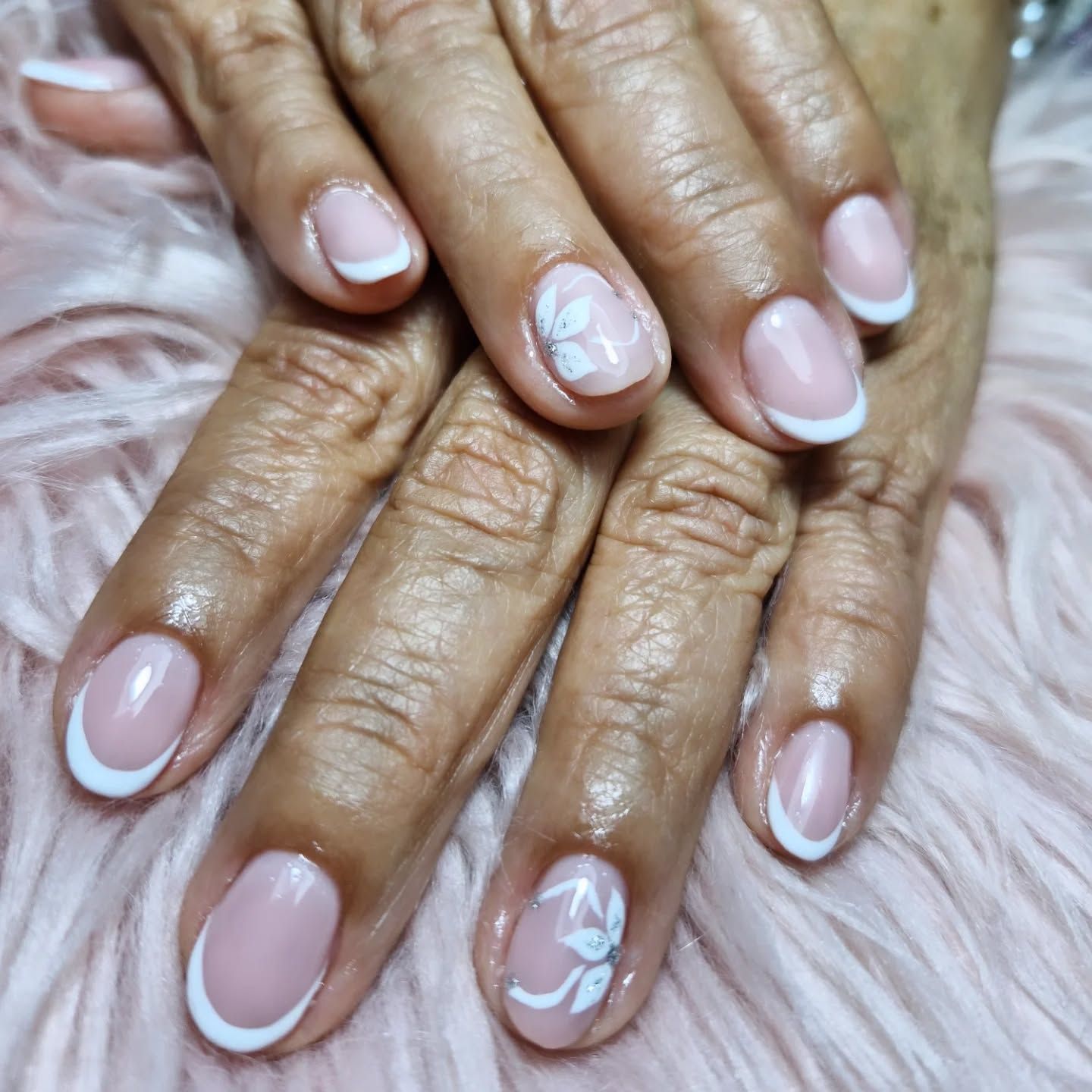 Unas manos con las uñas arregladas en color rosa pálido, juntas.