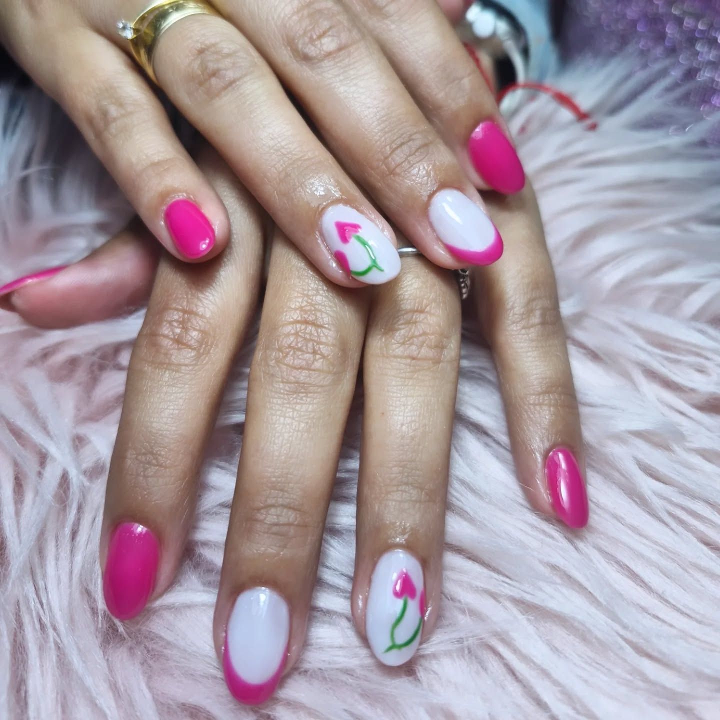 Manos con una manicura floral en rosa intenso y blanco, apoyadas sobre una superficie mullida.