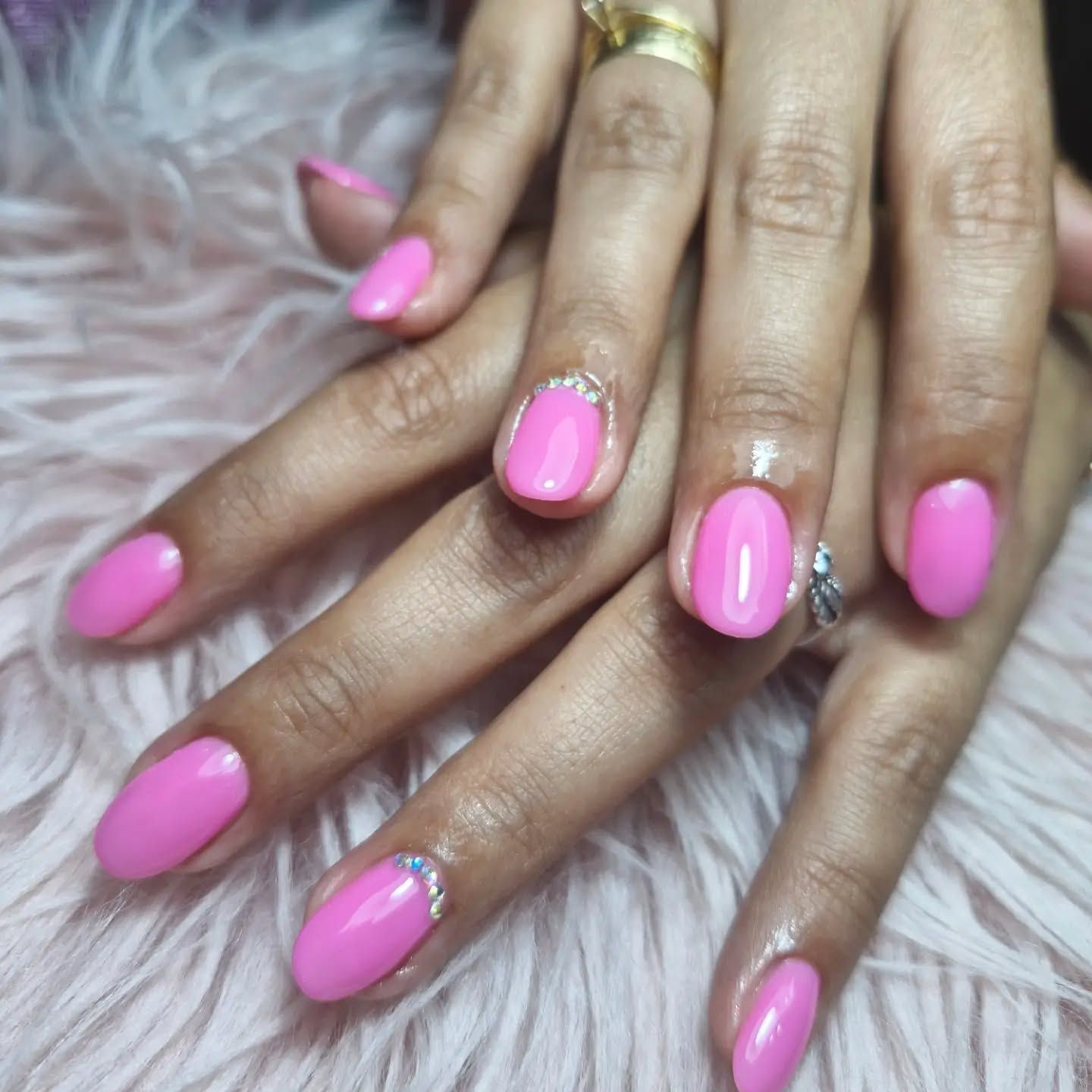 Manos con uñas cuidadas de color rosa brillante sobre un fondo blanco y esponjoso