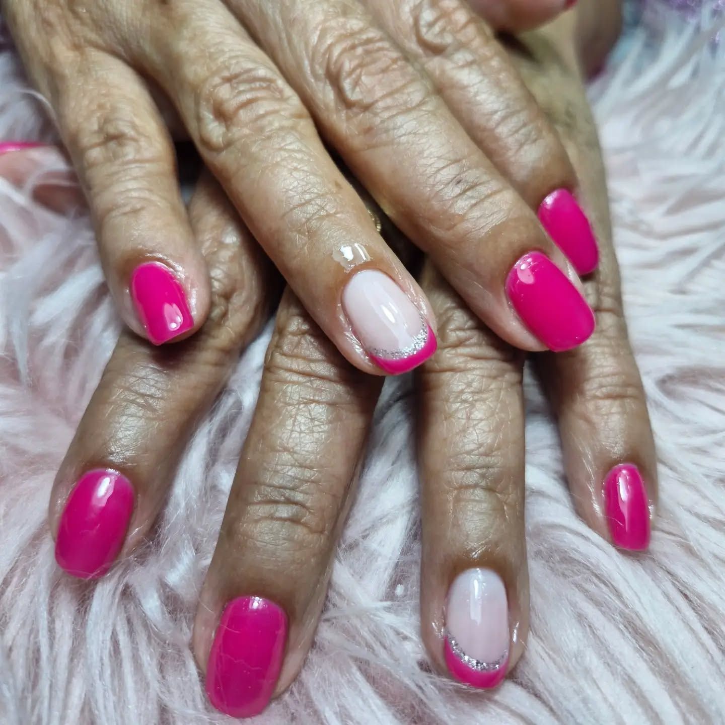 Manos con manicura en tonos rosa y nude, juntas sobre una suave superficie blanca con textura de piel