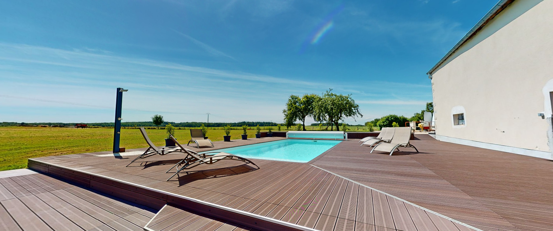 La terrasse du gîte avec des chaises longues et une piscine