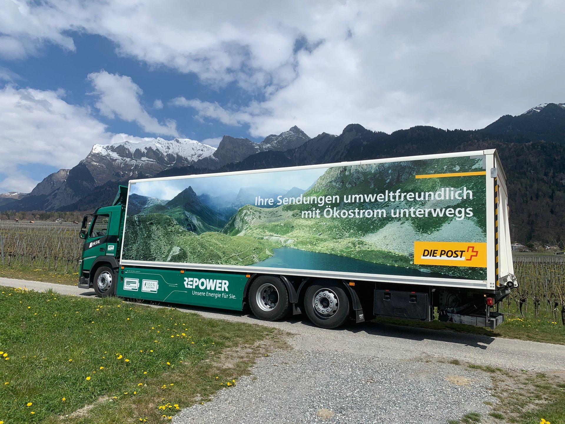 Ein LKW ist am Rand einer unbefestigten Straße geparkt. Im Hintergrund sind Berge zu sehen.