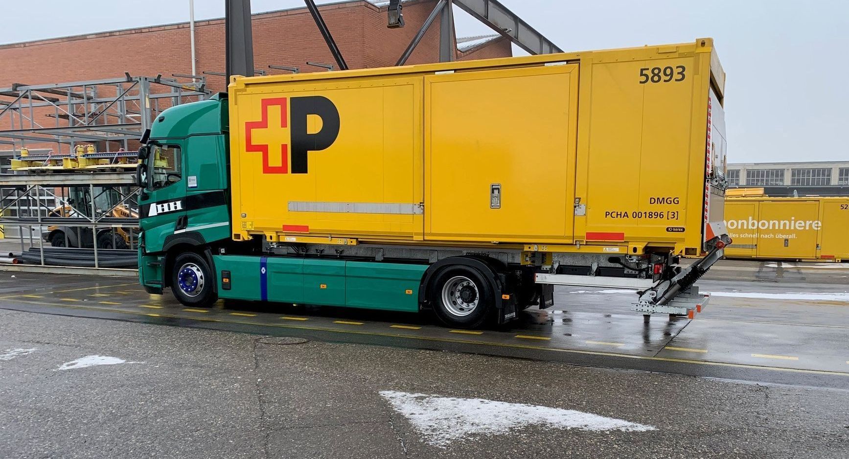 Ein gelber Lastwagen mit dem Buchstaben P an der Seite steht am Straßenrand.