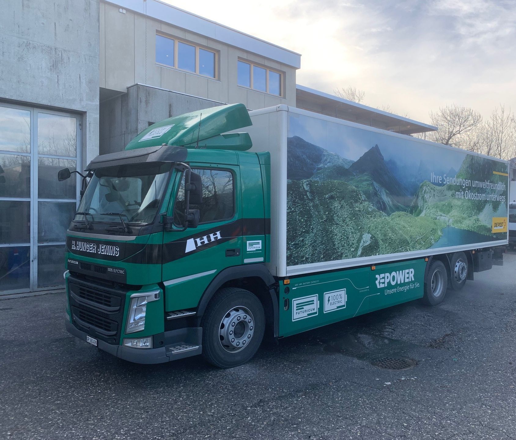 Ein grün-weißer Lastwagen steht vor einem Gebäude.