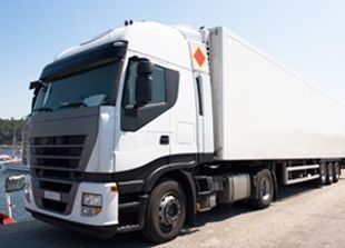 Un camión semirremolque blanco está estacionado al lado de un cuerpo de agua.