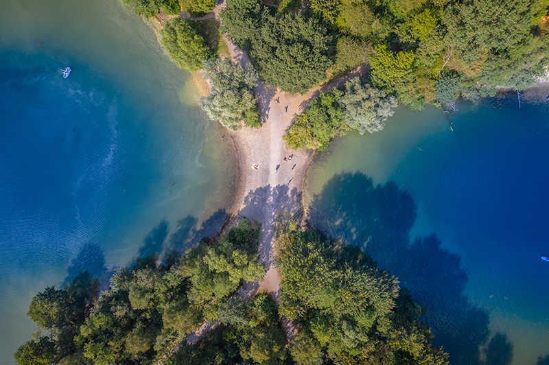 Sechs-Seen-Platte Duisburg (Six Lakes Plateau). An aerial view of a lake surrounded by trees and a road.