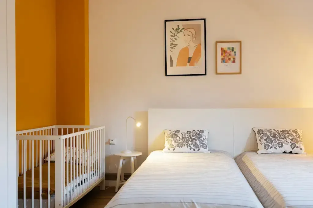 A bedroom with two beds and a crib.