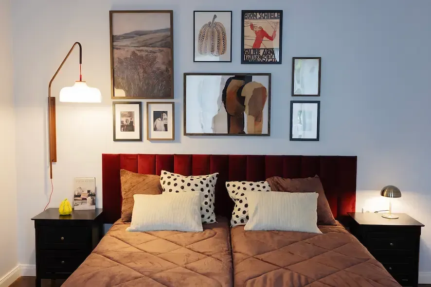 A bedroom with a bed and a wall with pictures on it