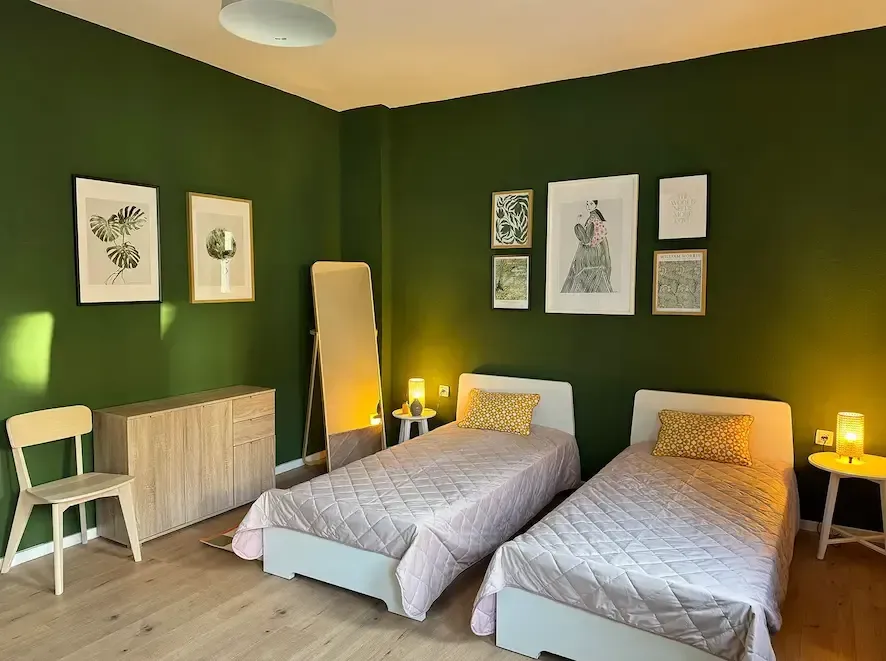 A bedroom with two beds and green walls