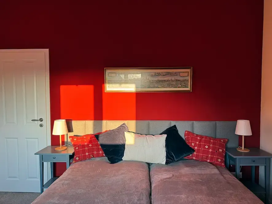 Ein Schlafzimmer mit einer roten Wand und einem Bett