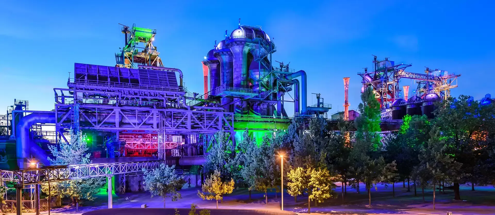 Landschaftspark Duisburg-Nord. A large building with a lot of lights on it is lit up at night.