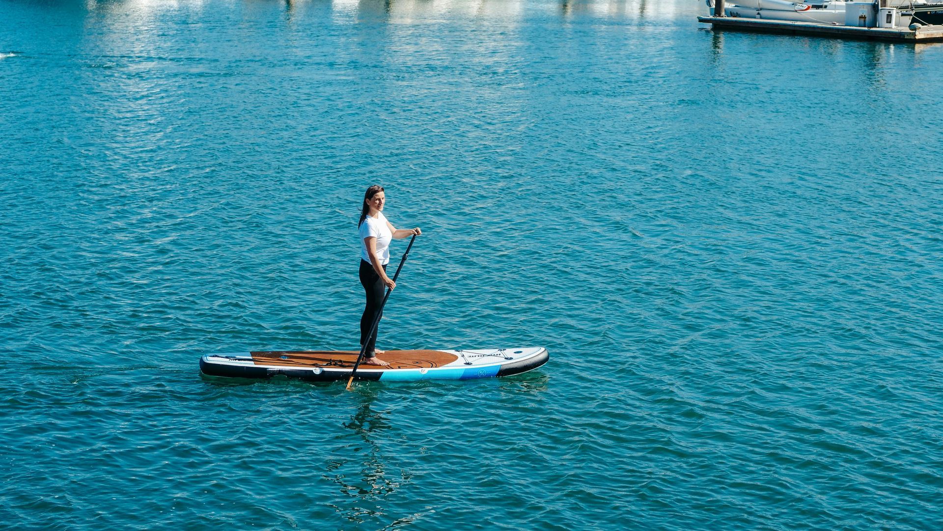 Eine Frau steht auf einem Paddleboard im Wasser.