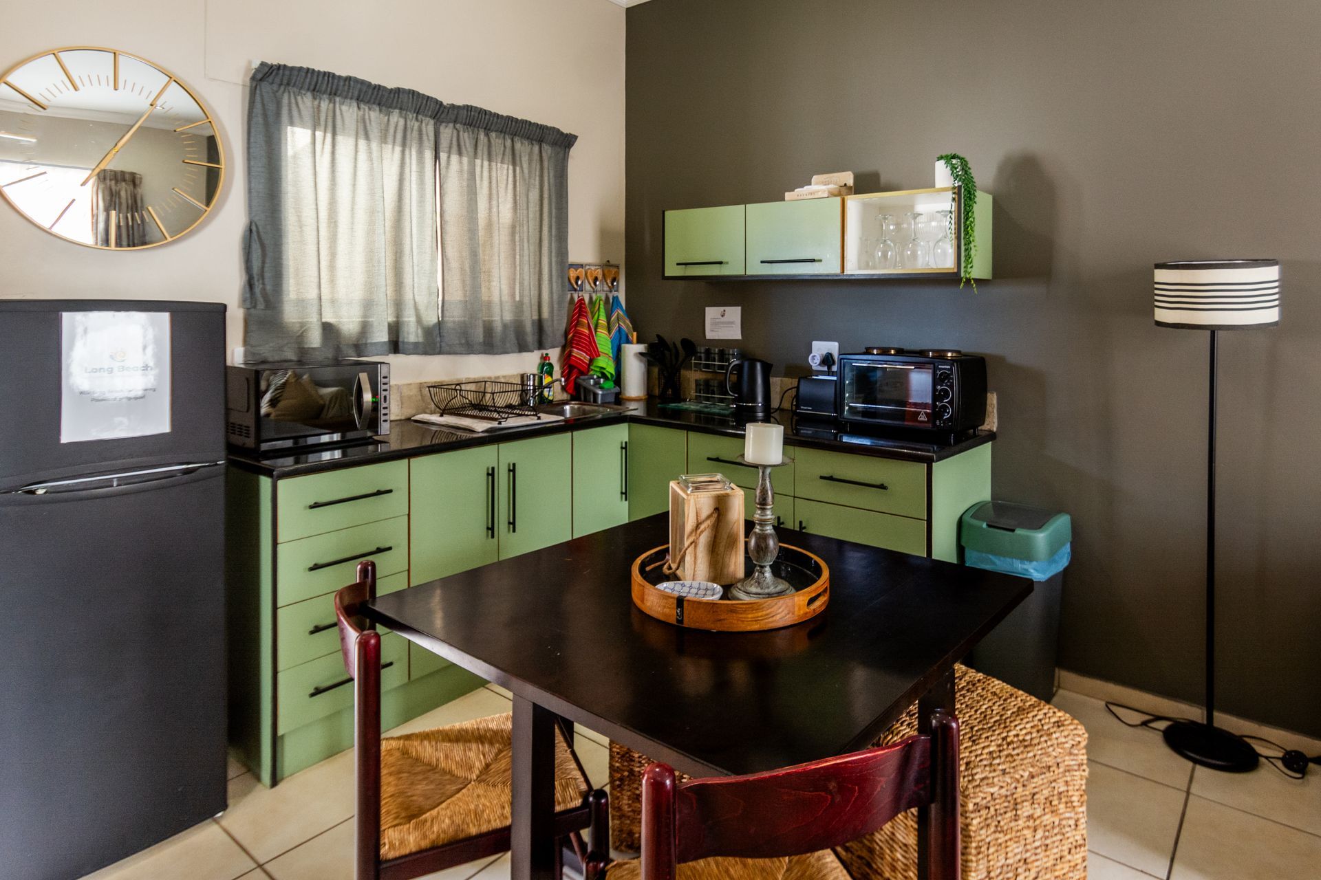 Kitchen with green cabinets, black appliances, a square table, and a mirror.