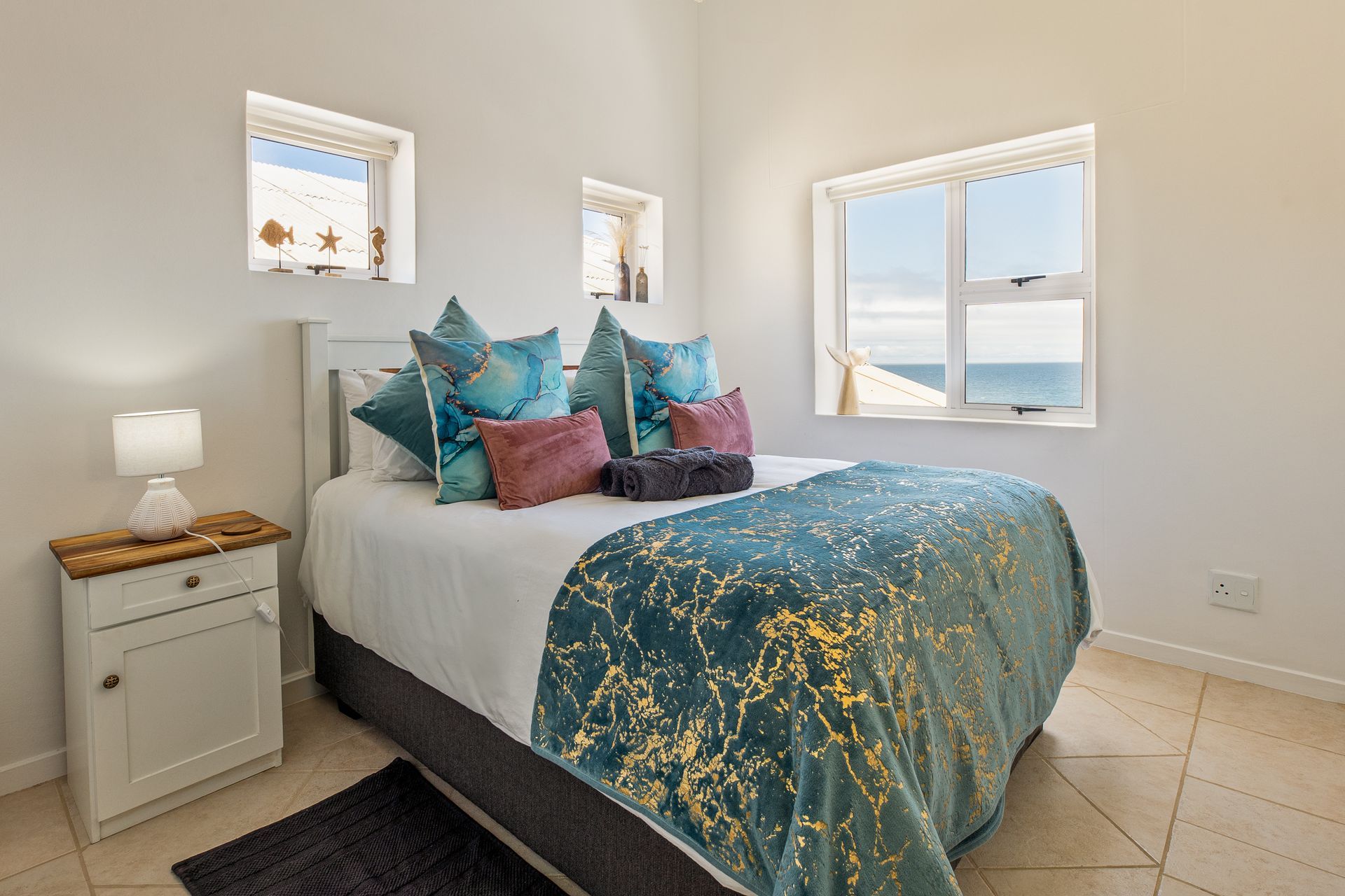 Bedroom with bed, pillows, and a window with ocean view.