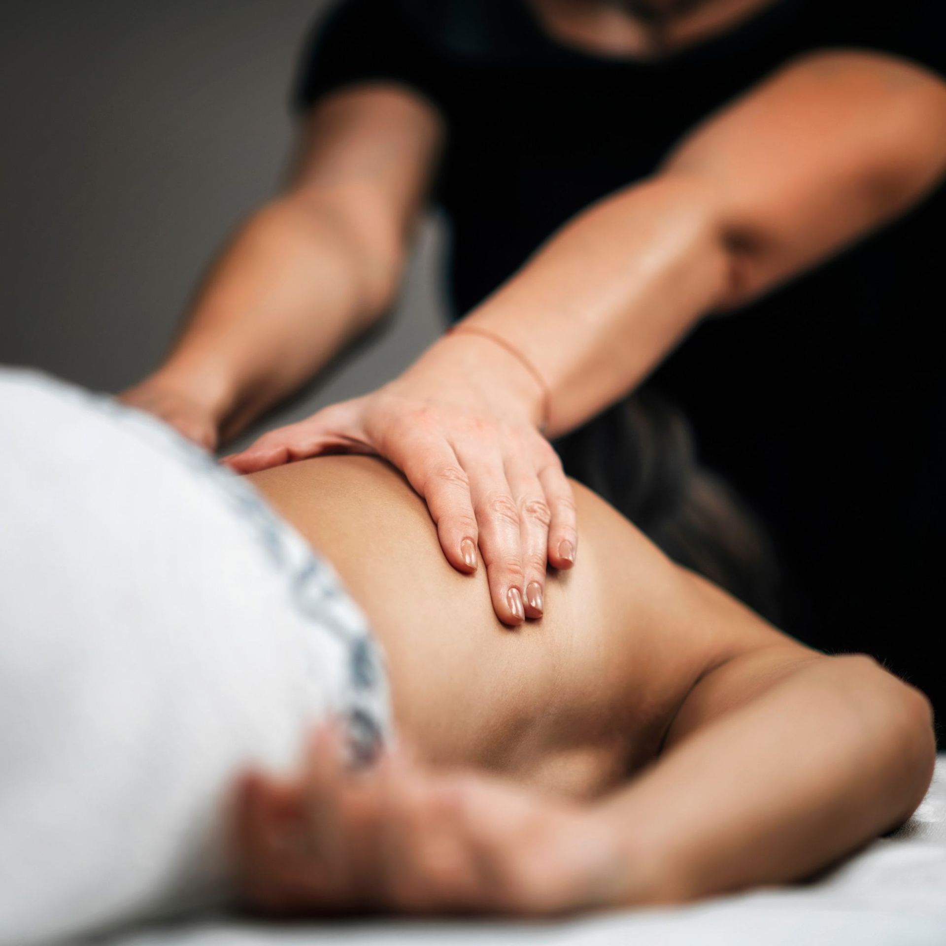 Una mujer está acostada en una cama recibiendo un masaje.