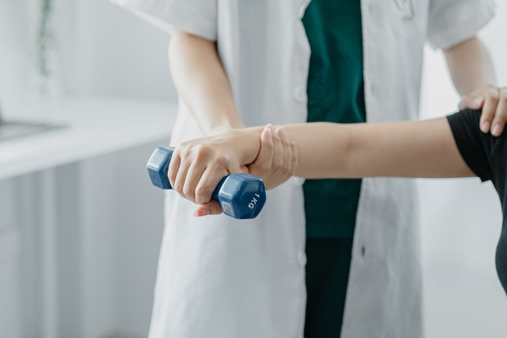 Un médico está ayudando a un paciente a levantar una mancuerna.
