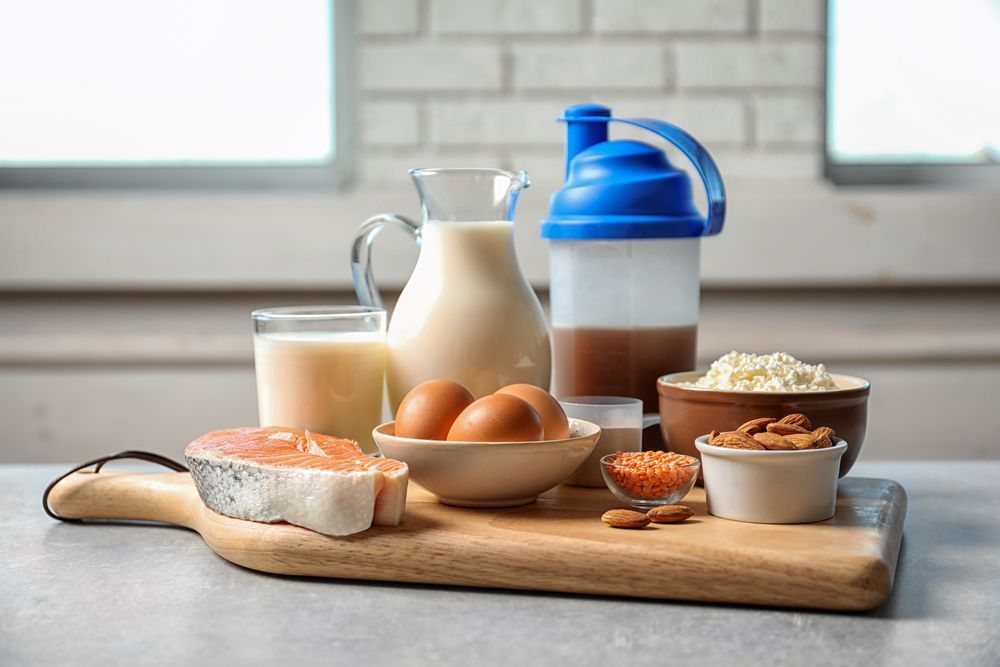Una tabla de cortar de madera cubierta con una variedad de alimentos proteicos.