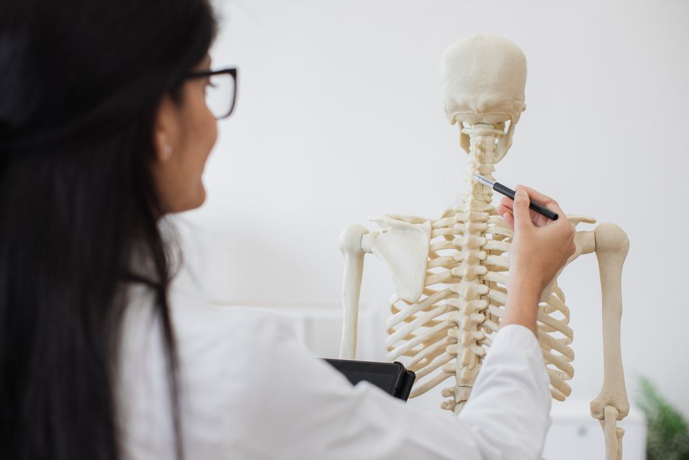 Una médica está dibujando un esqueleto con un marcador.