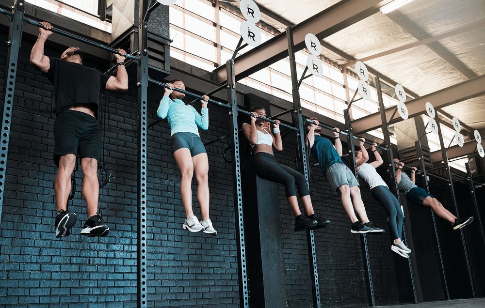 Un grupo de personas está haciendo dominadas en una pared de un gimnasio.