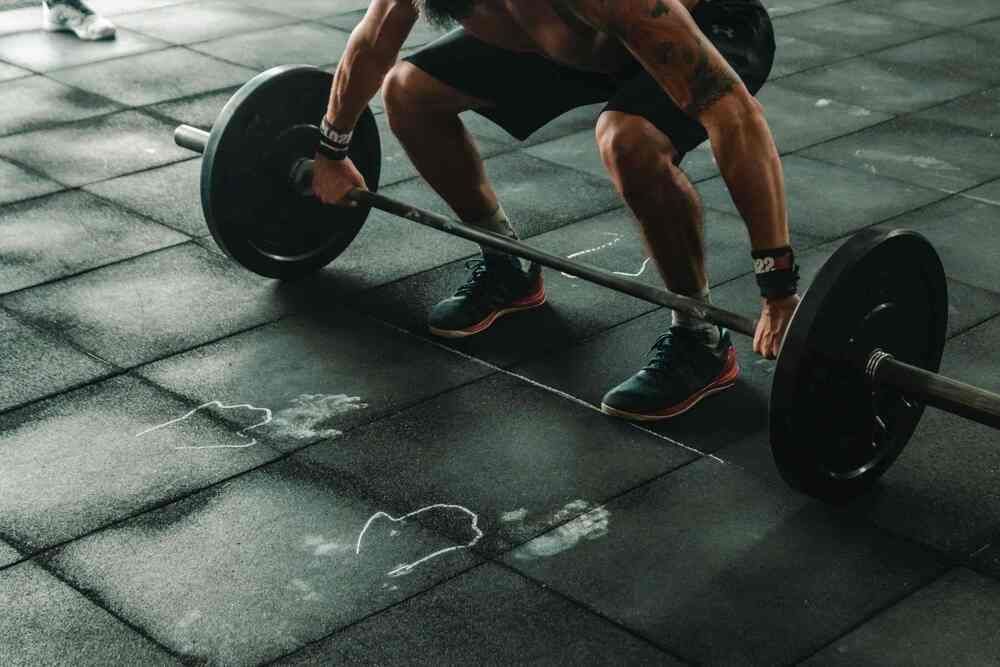 Un hombre se pone en cuclillas para levantar una barra en un gimnasio.