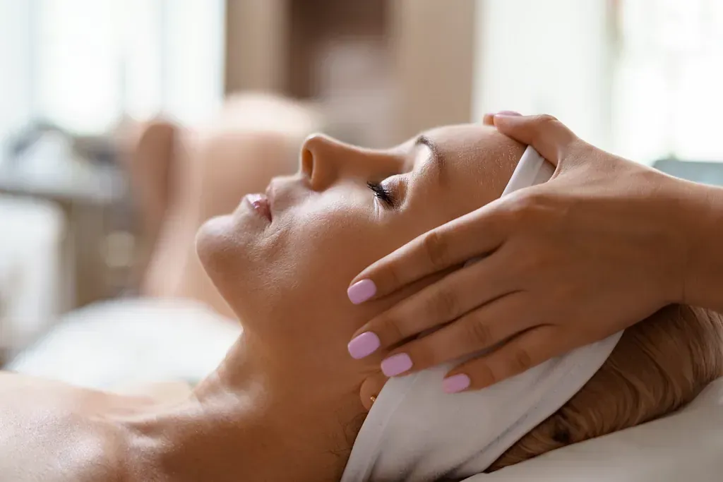Una mujer está recibiendo un masaje facial en un spa.