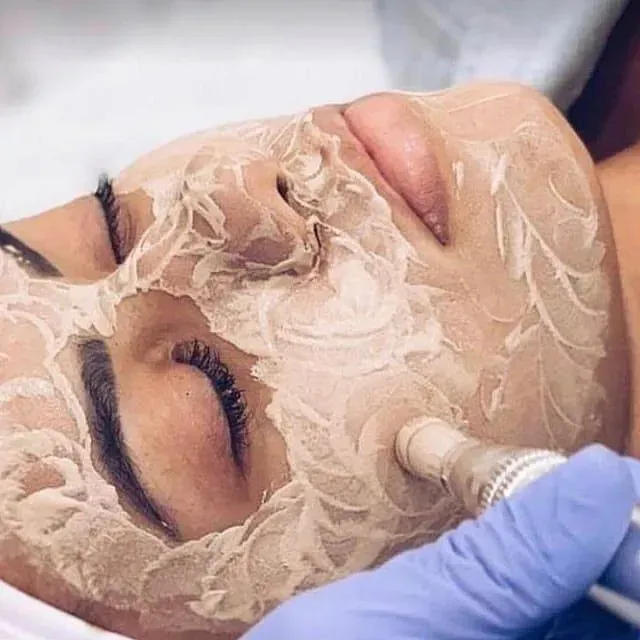 Una mujer está recibiendo un tratamiento facial con una mascarilla en la cara.