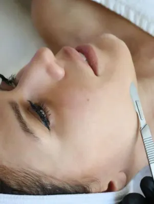 Una mujer está recibiendo un tratamiento facial con un bisturí.