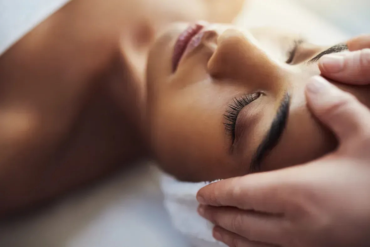 Una mujer está recibiendo un masaje de cabeza en un spa.