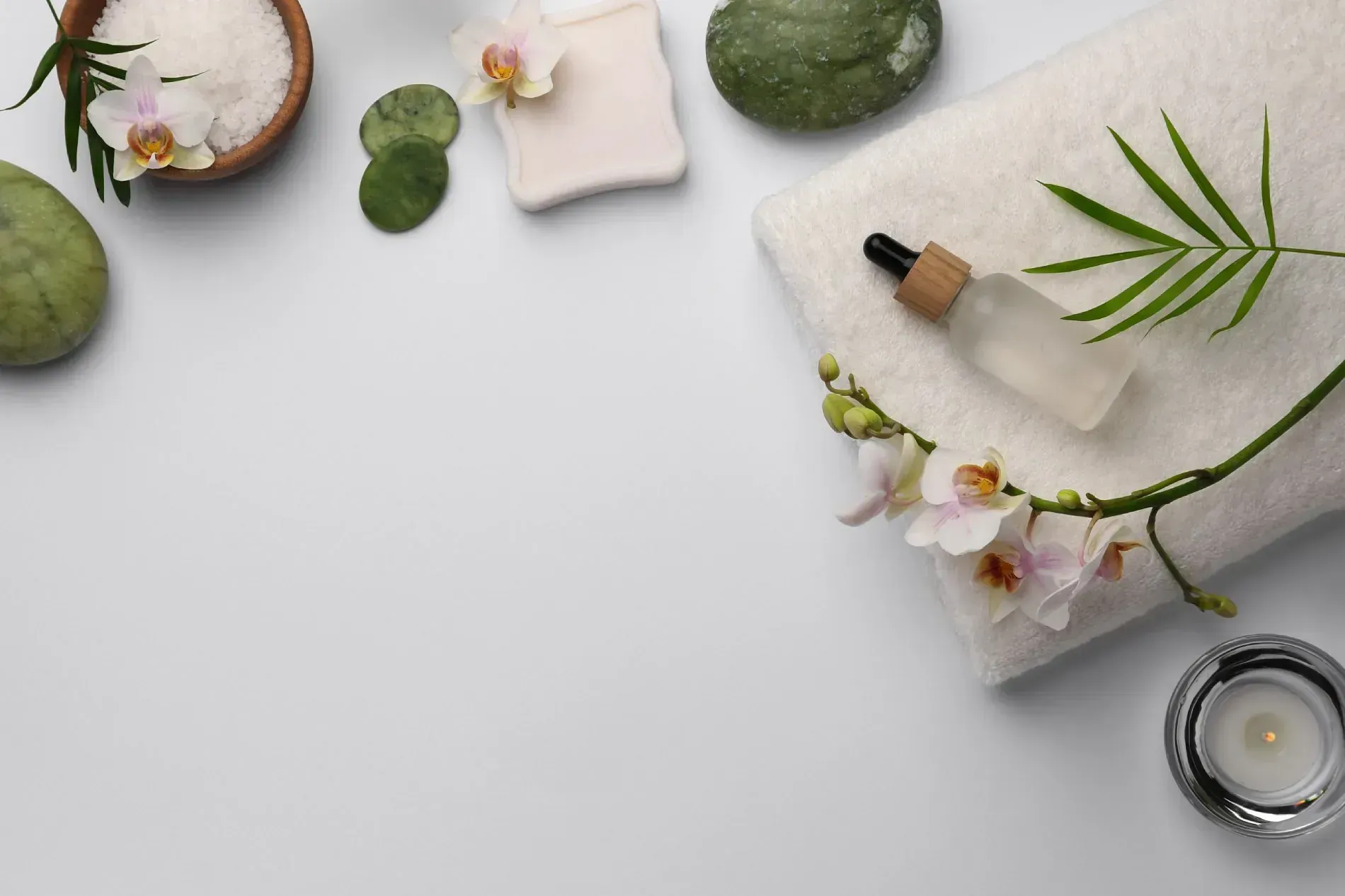 Una toalla blanca con flores y una botella de loción encima.