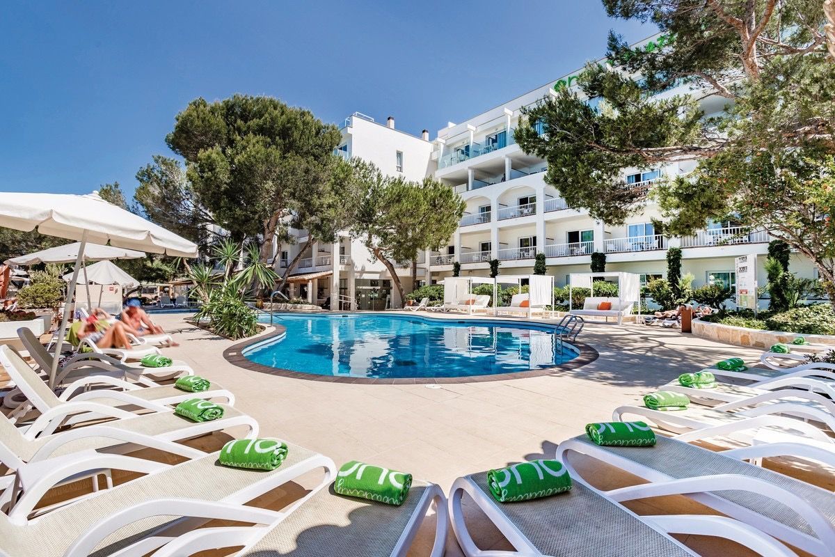 Una gran piscina rodeada de sillas y sombrillas frente a un hotel.