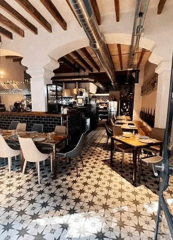 Un restaurante con mesas y sillas y un suelo de baldosas en forma de estrella.