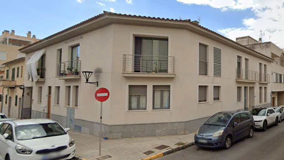 Un coche blanco está aparcado delante de un edificio con una señal de prohibido el paso.