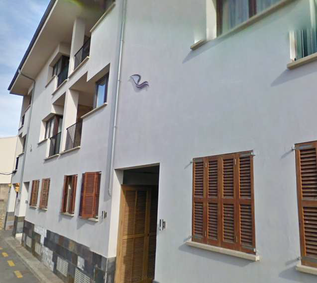 Un edificio blanco con contraventanas de madera en las ventanas.