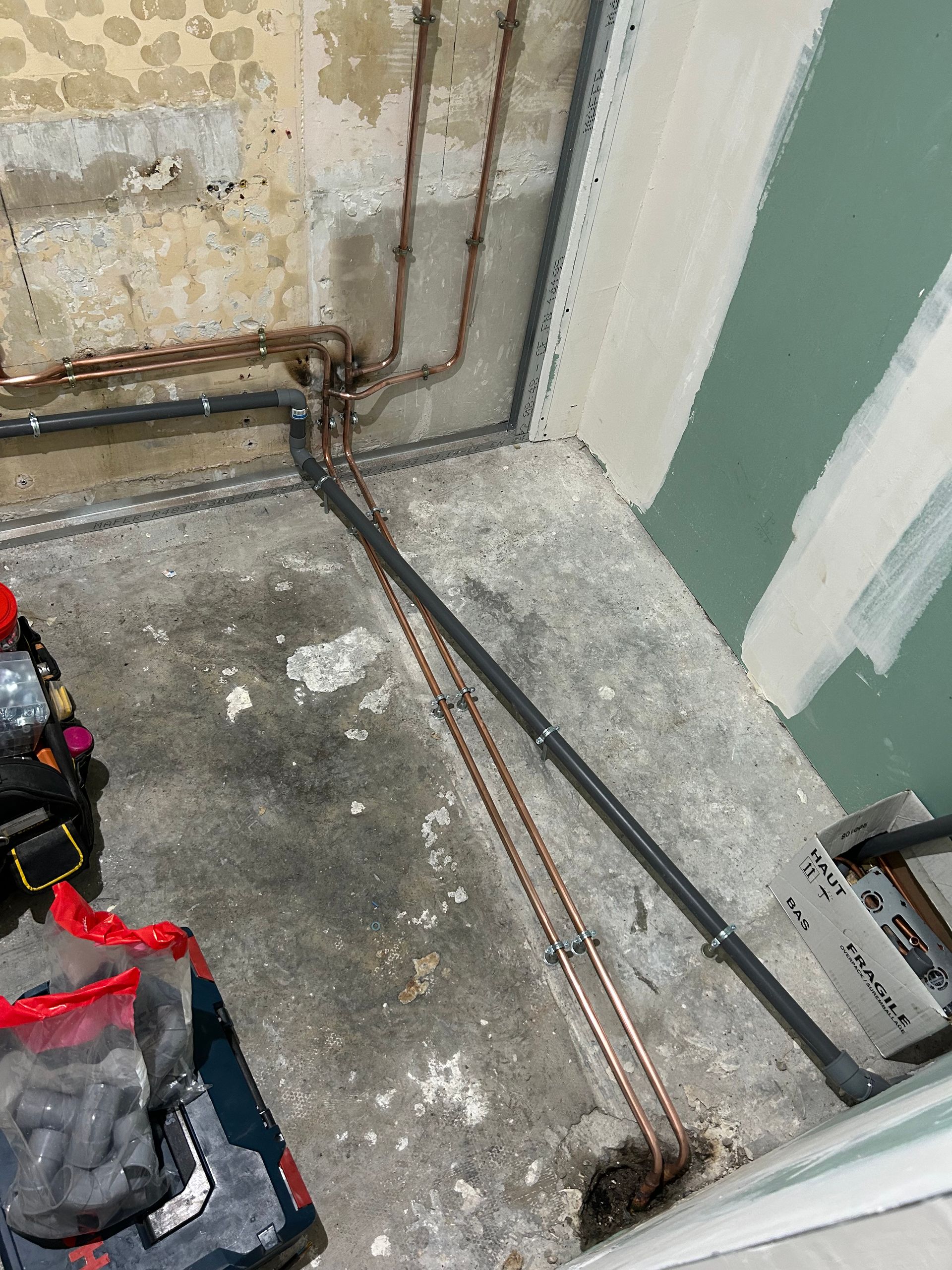 Tuyaux en cuivre et acier le long d'un sol et mur