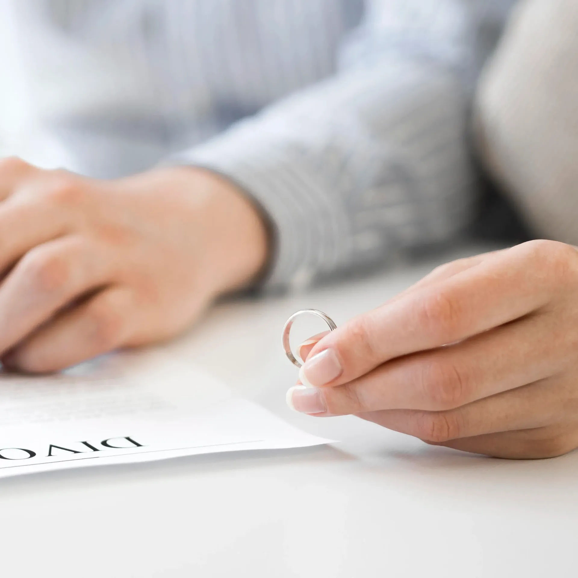 Una persona sostiene un anillo de bodas sobre un documento en el que se ve la palabra 