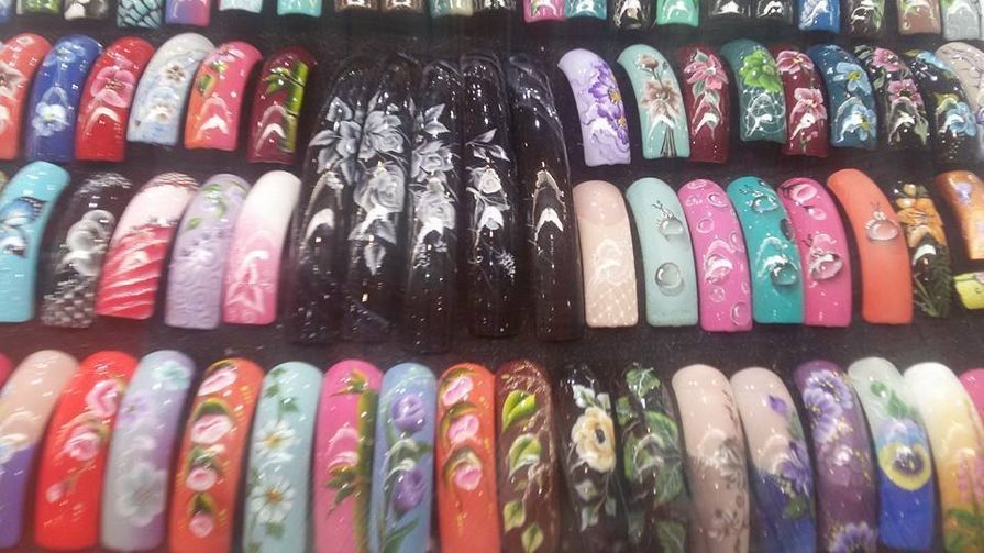 Coleção de designs coloridos de unhas acrílicas com padrões florais e abstratos.