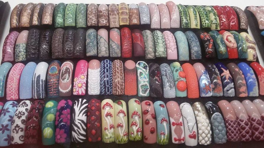 Fileiras de unhas postiças coloridas e decoradas.