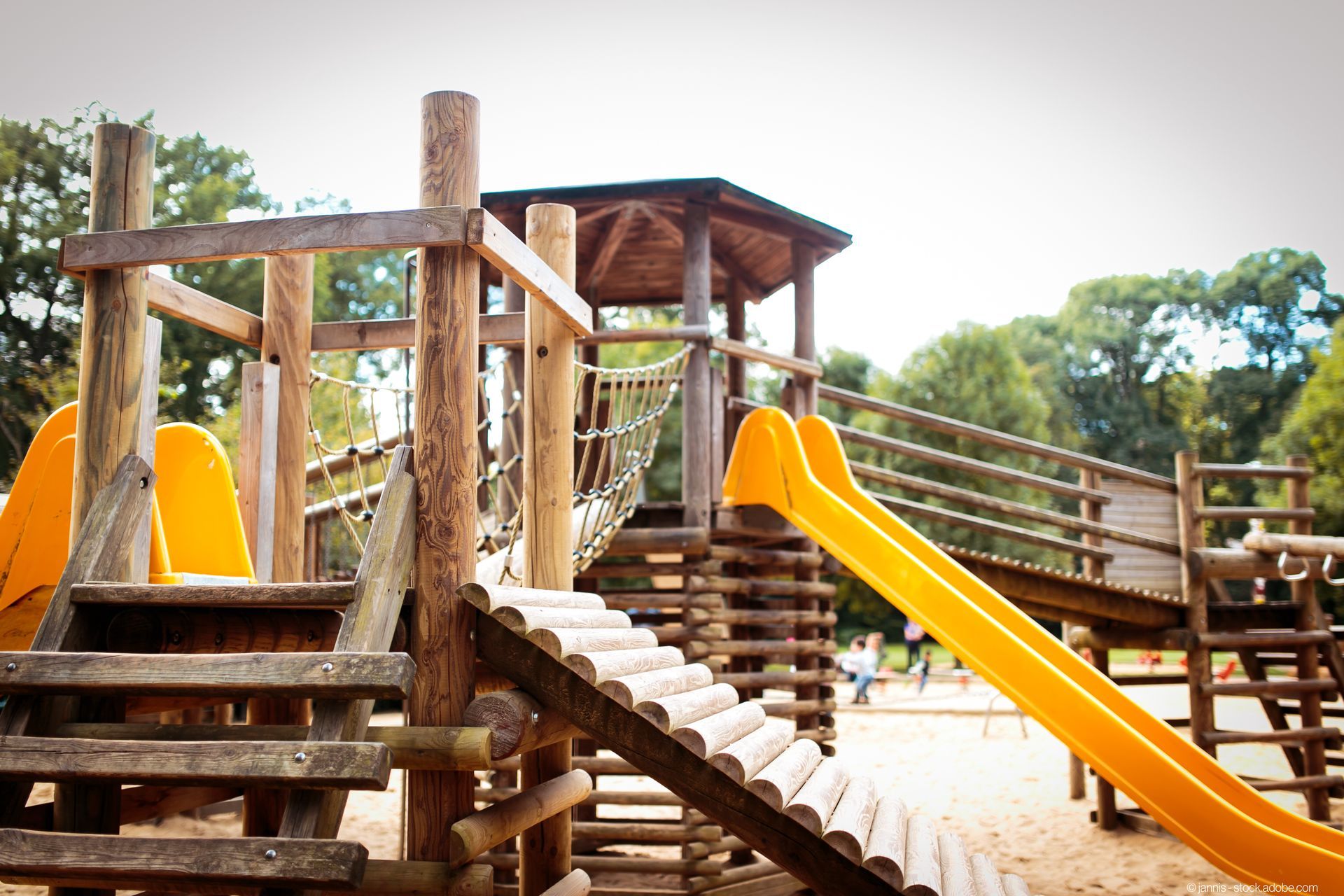 Großes Kinder-Klettergerüst aus Holz auf einem Spielplatz mit Rutschen, Brücken und Sandkästen
