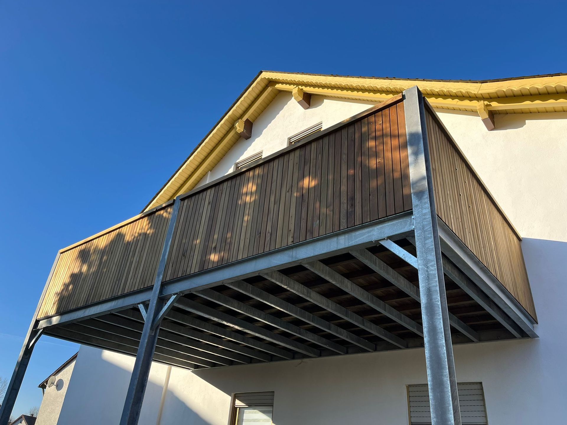 Nachträglich angebauter Balkon mit Metallgestell und Holzverkleidung