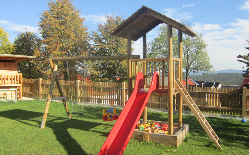 Kinder-Klettergerüst aus Holz mit Schaukel, Rutsche und Sandkasten in einem Garten